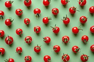 Pattern of ripe red cherry tomatoes on green background, a Food & Drink Photo by AlyaAnd