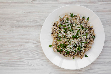 Homemade mushroom risotto with parsley on a white plate on a whi, a Food & Drink Photo by LiudmylaChuhunova