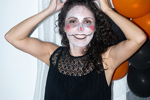 Woman with Halloween makeup holding pumpkin decoration on her head, a Person Photo by etorres69