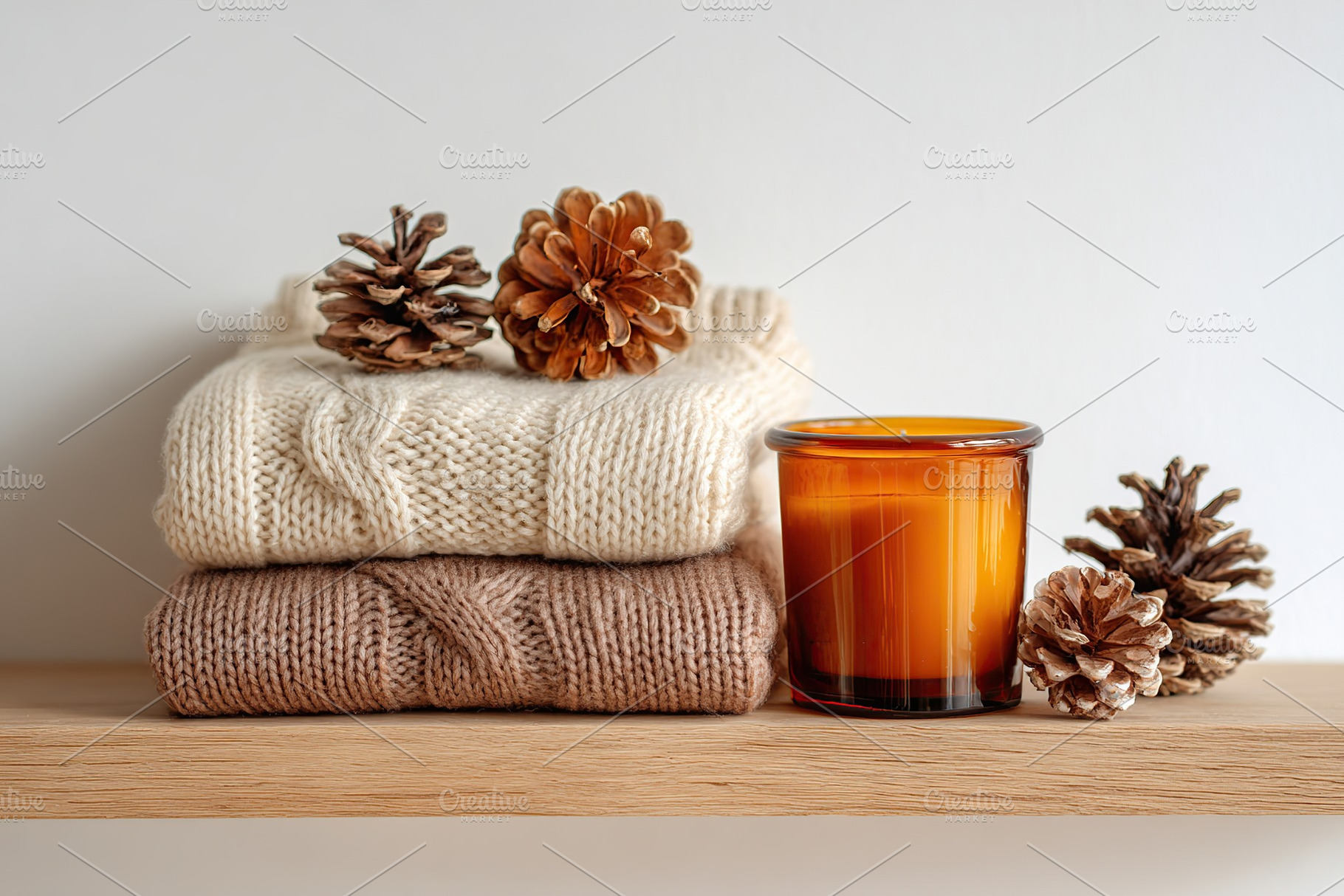 Cozy wool sweaters neatly folded on a wooden shelf with decorative elements and, a Photo by AlyaAnd