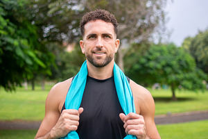 Smiling athletic man resting after fitness workout in green park