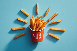 Fries arranged like sun rays create a playful food display in bright colors, a Food & Drink Photo by AlyaAnd