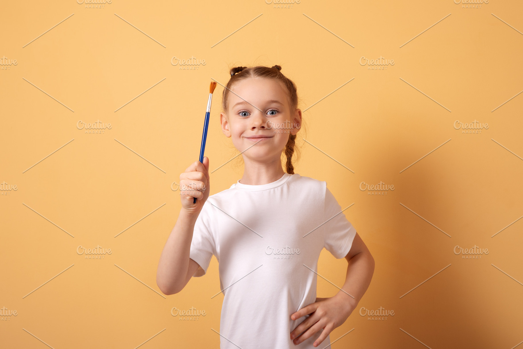 Cheerful young girl in a white t-shirt holding a paintbrush agai, a Person Photo by Ales Munt