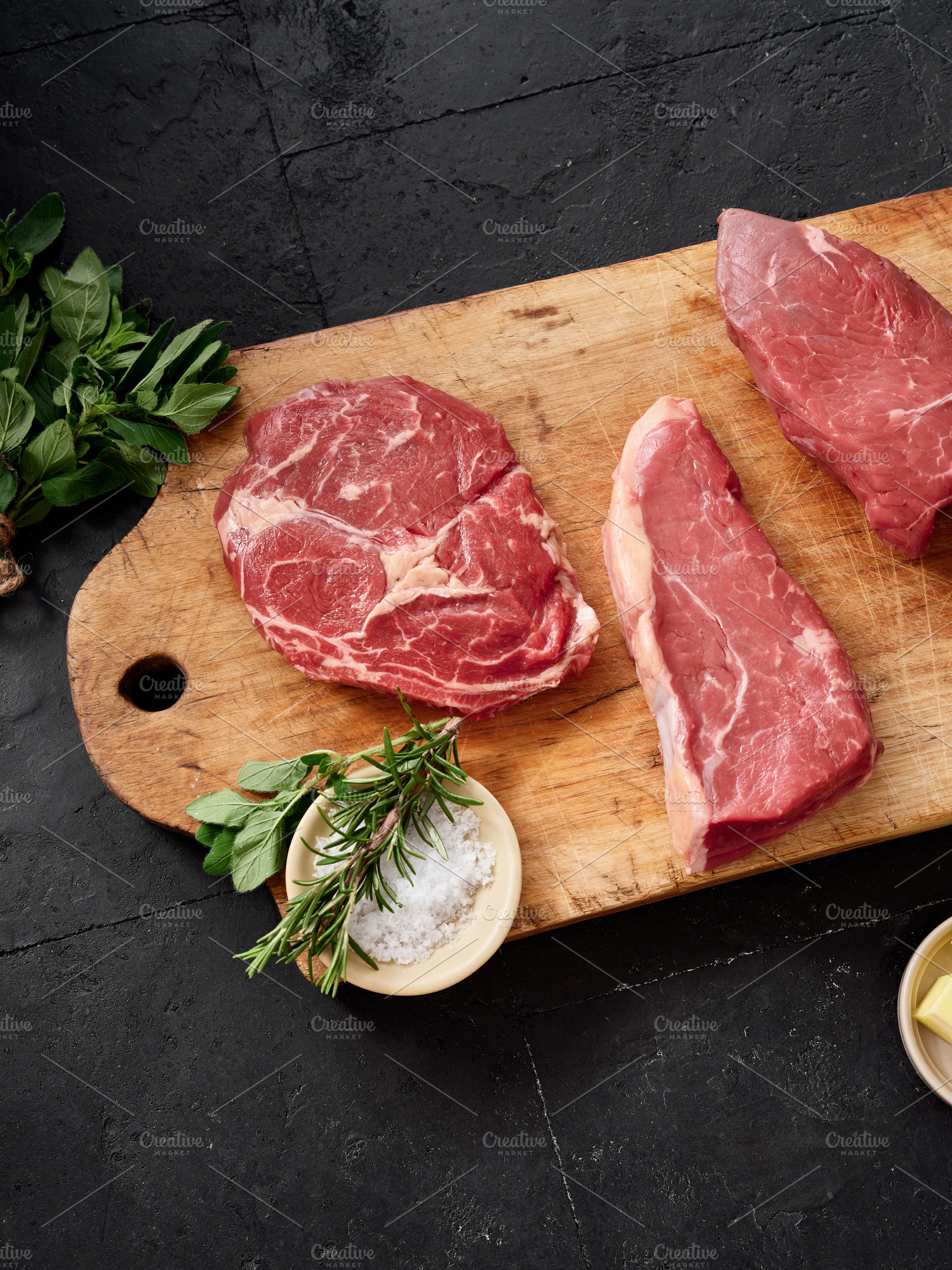 Raw rib-eye, roast beef, flank and rump steak on a wooden cutting board placed, a Food & Drink Photo by Asya Nurullina
