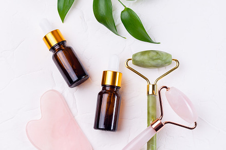 Crystal facial roller and massage tool Gua sha with brown cosmetic bottles and, a Beauty & Fashion Photo by iuliia_n