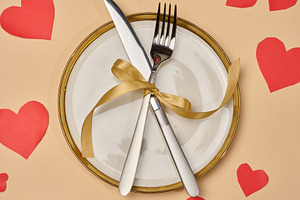 White plate with golden rim and cutlery tied with ribbon on beig, a Holiday Photo by ndanko