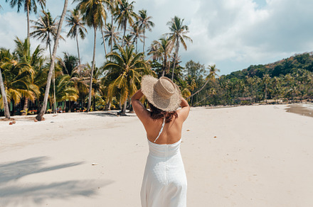 A woman in a hat enjoys the summer sun on a beautiful tropical b, a Holiday Photo by Art Rachen