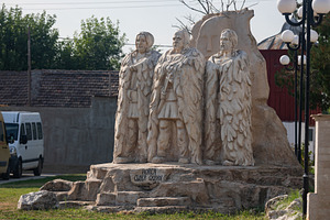 Stone sculpture depicting three historical figures in traditional attire, outdo, an Architecture Photo by Ales Munt