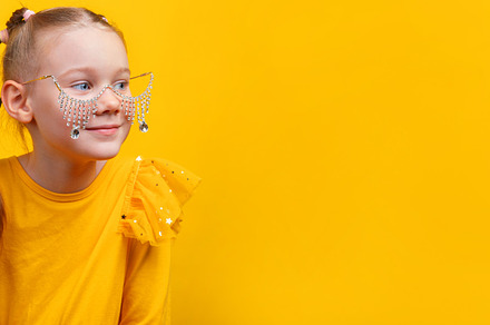 Cheerful girl in yellow dress with jeweled glasses looking sidew