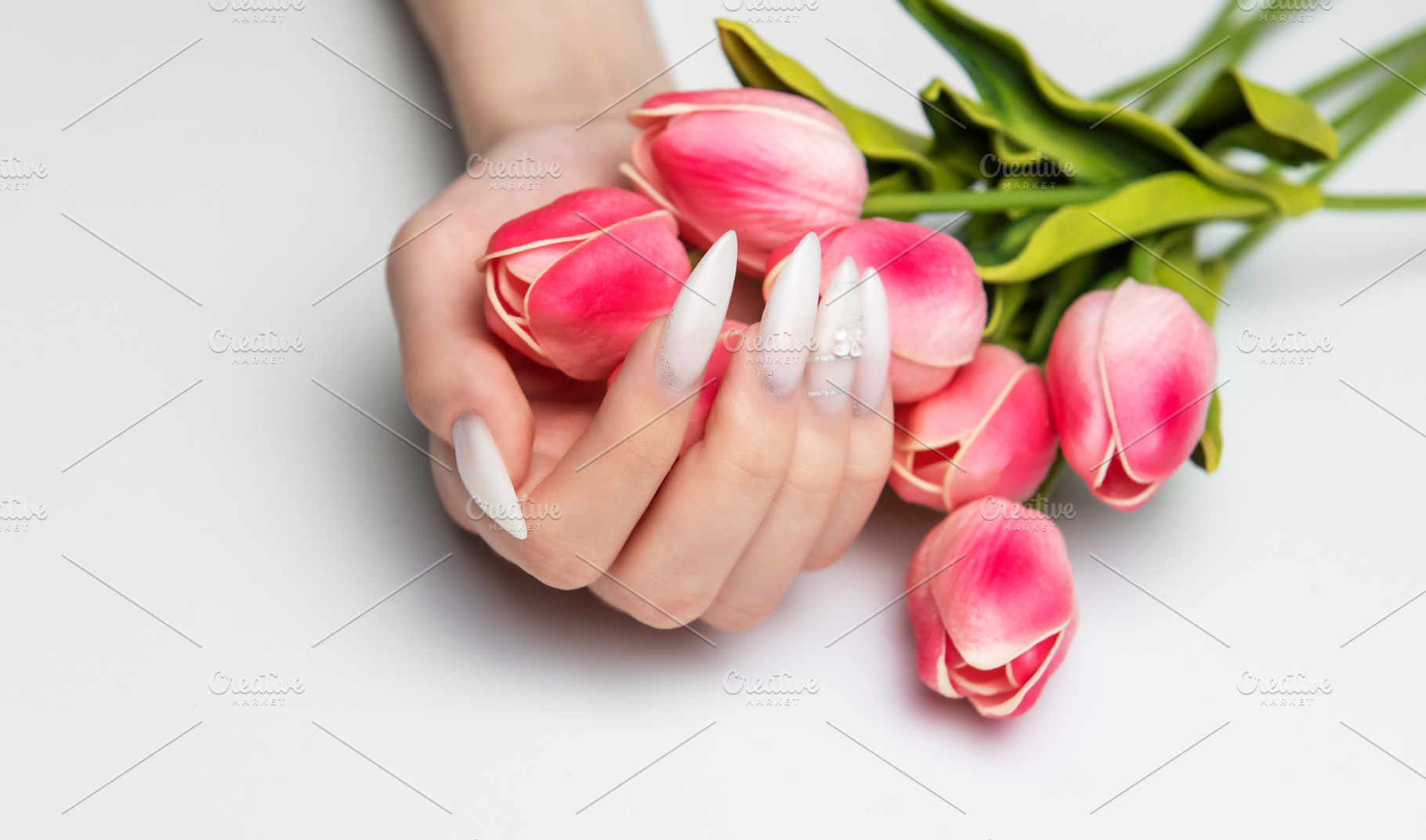 Hand holding pink tulips displaying long white nails, a Beauty & Fashion Photo by Olena Rudo