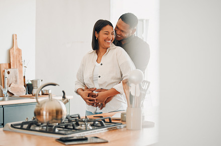 Loving, happy and hugging couple relaxing in the kitchen at home smiling and laughing together. Carefree, excited and affectionate lovers having fun and enjoying quality time in the house, a Photo by Peopleimages.com