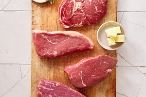 Raw rib-eye, roast beef, flank and rump steak prepared on a wooden cutting boar
