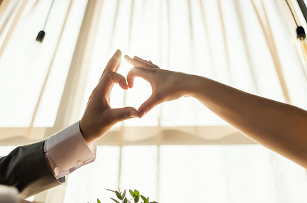 Female and male hands forming a heart shape with sunlight at restaurant interior. Concept of love, wedding., a Person Photo by Northern Life