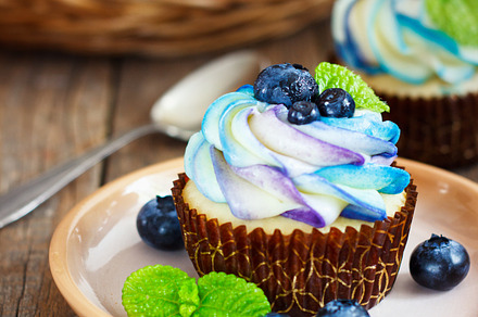 Gentle cupcake with cream and berries on adark wood background featuring
