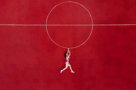 Abstract aerial shot of woman in swimwear hanging holding a circle on basketbal