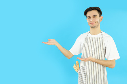 Concept of cooking, young man in apron on blue background, a Person Photo by AtlasStudio PRO