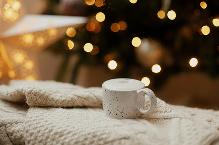 Warm cup of coffee on background of christmas tree with lights., a Holiday Photo by Sonjachni