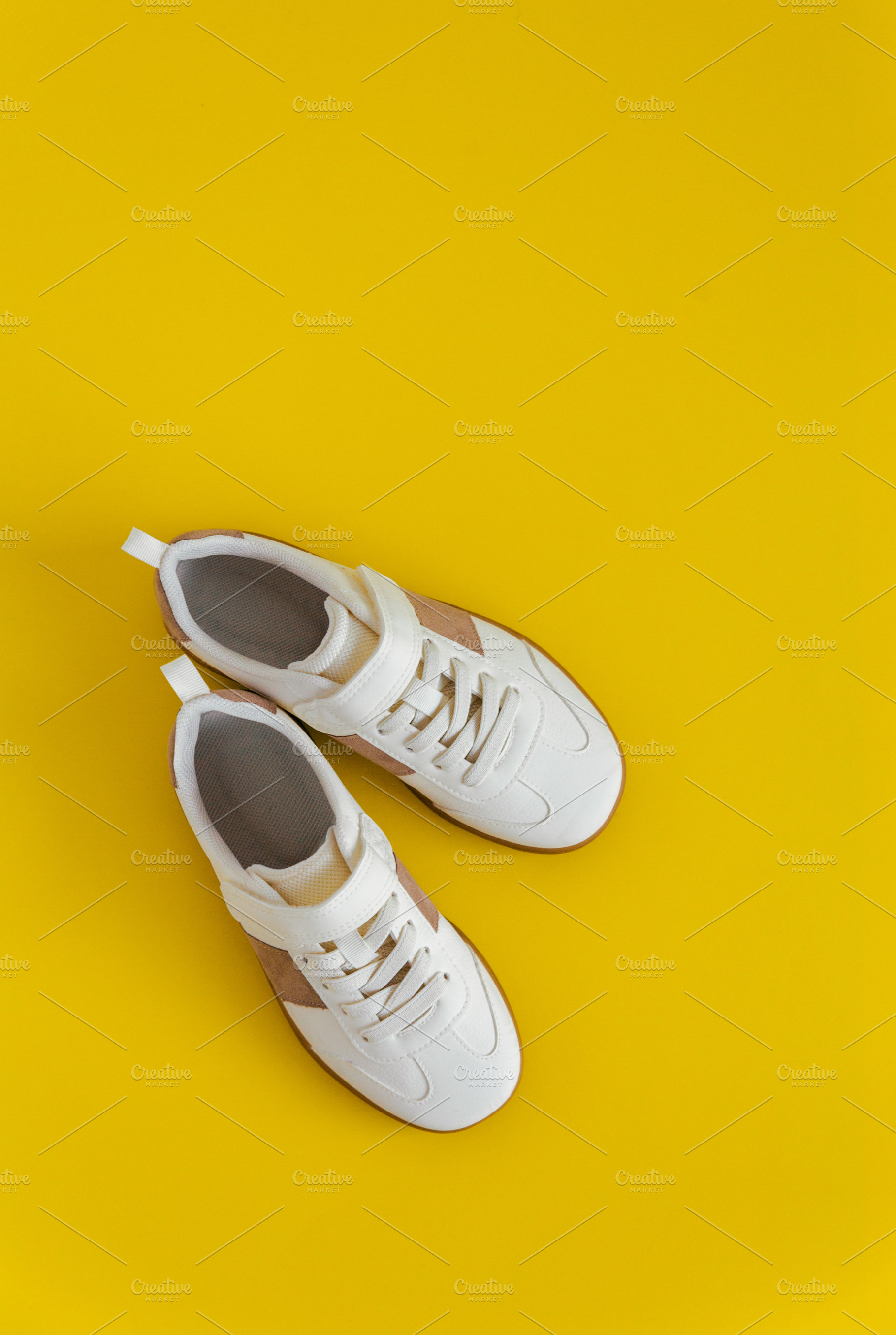 White kids sneakers,yellow backgroun, a Beauty & Fashion Photo by Kolomiyets Viktoriya