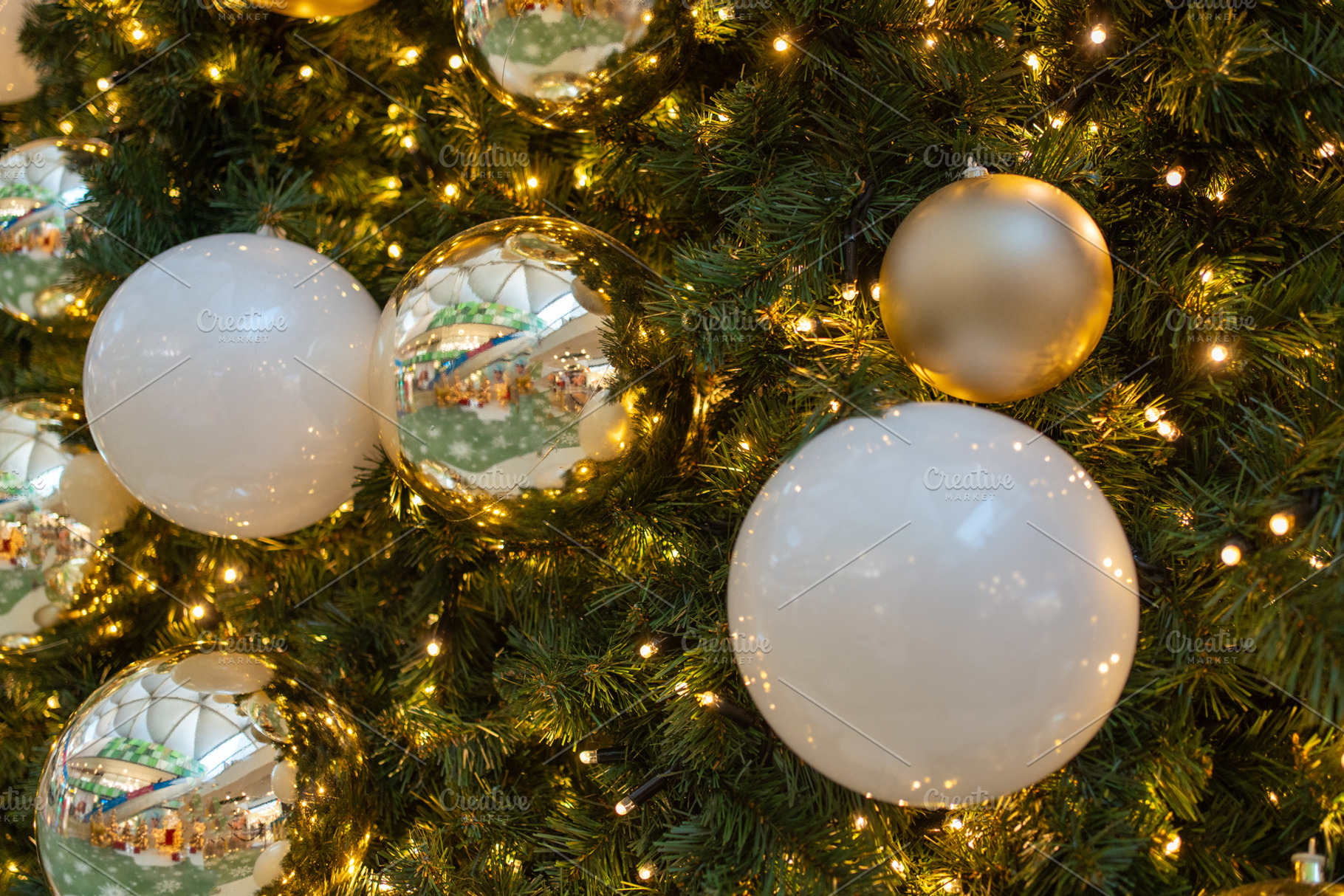 Closeup of shiny golden baubles hanging on illuminated Christmas tree, a Photo by andreonegin market