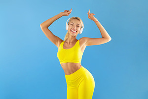 Smiling Young Woman In Sportswear Listening To Music And Dancing, a Photo by Prostock-Studio
