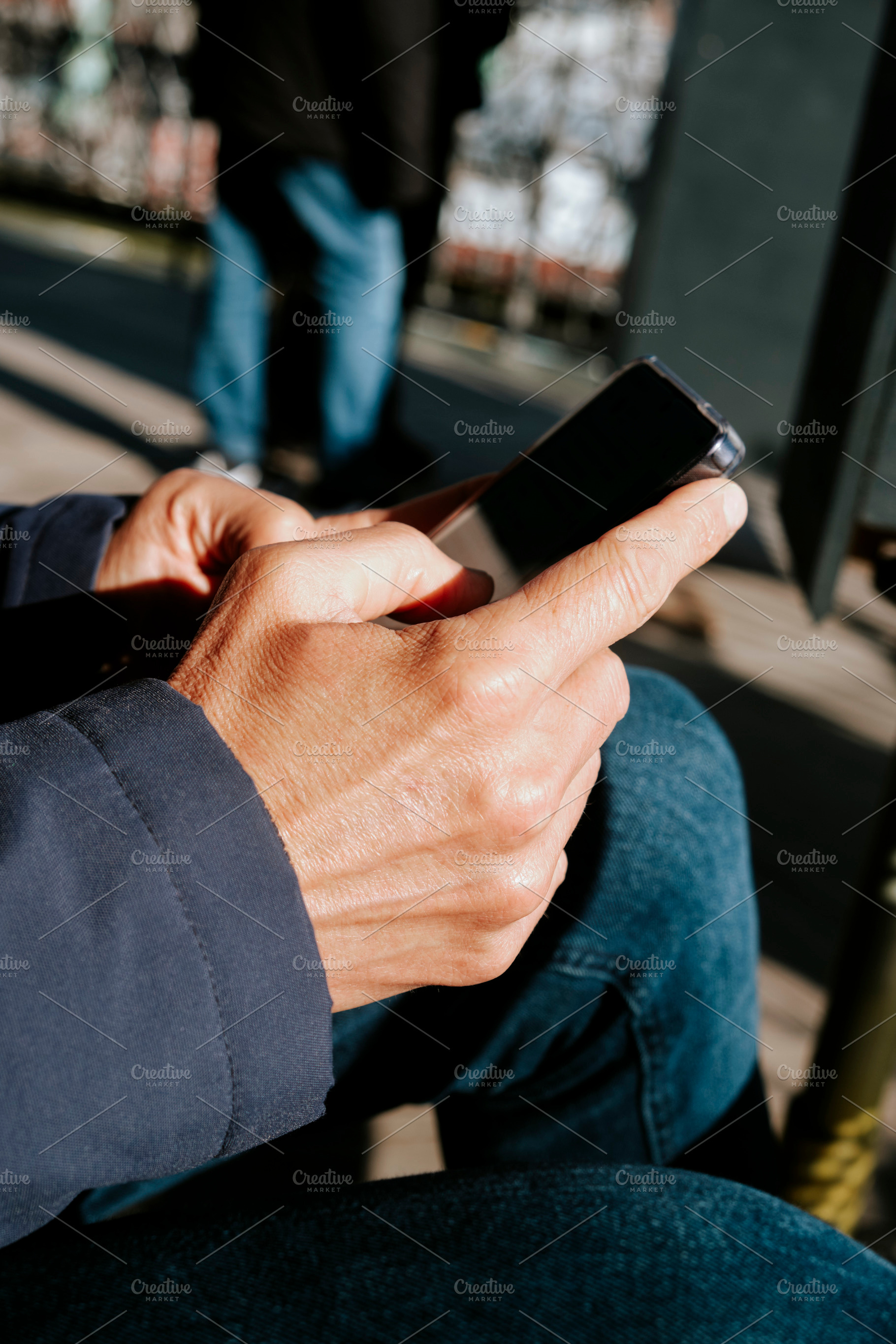 a man uses a smartphone while seated outdoors, a Photo by Nito