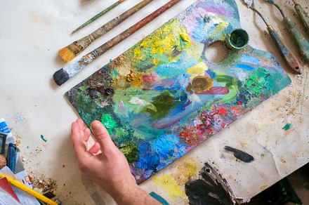 Palette of an artist with brushes containing paint, artist, and brush