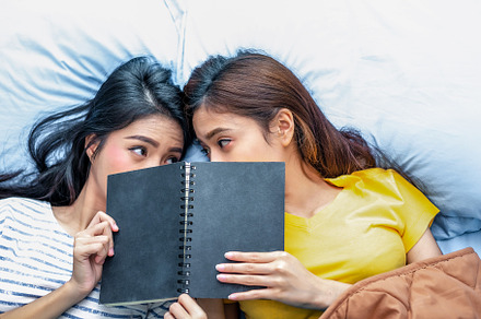 Cute Asian lesbian couple reading book together and lying on bed, a Person Photo by Ministocker