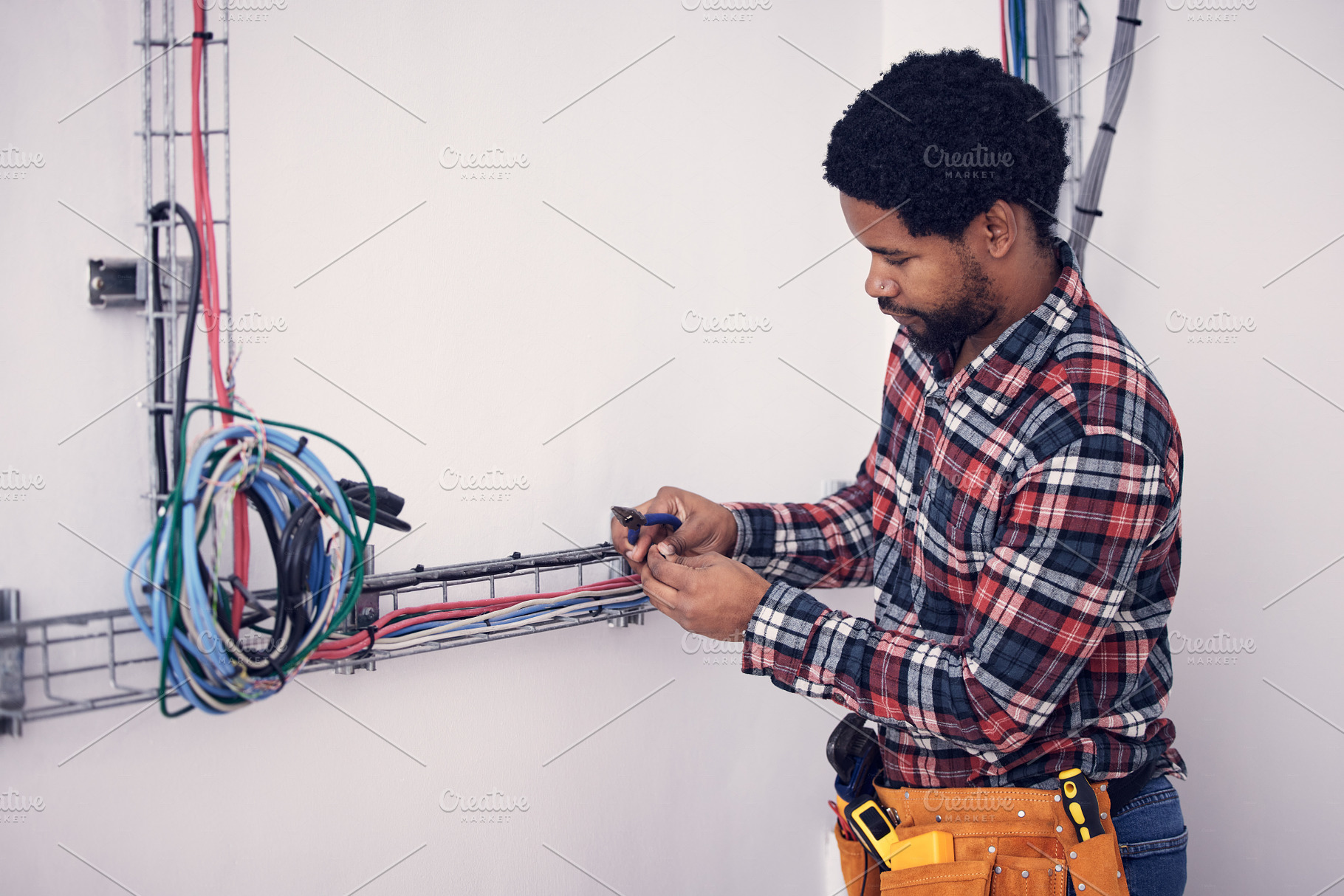 Technician, black man and electrician checking cables, fixing faulty wires and server mechanic. Male employee, entrepreneur and engineer with tools, electrical and maintenance with handyman and focus, a Photo by Peopleimages.com