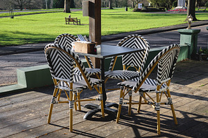 Empty outdoor cafe seating with bistro chairs on wooden deck ove, a Photo by Studio ANNA