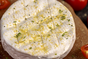 white soft cheese in salt and spices and small red round tomatoes on the table, a Photo by rsoollAI