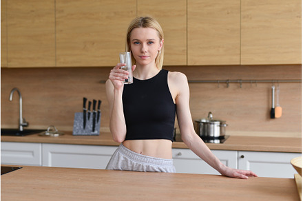 Woman drinking water in kitchen, a Person Photo by undrey