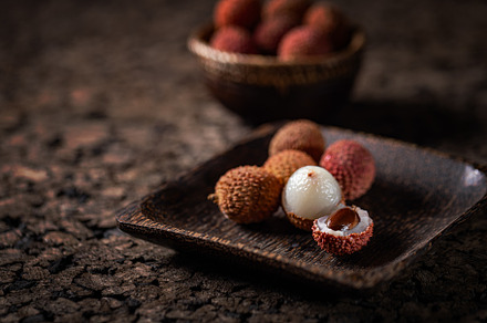 Fresh lychees are served on a wooden tray, a Photo by Grafvision photography