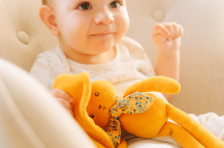 Portrait of a nine month old baby with a stuffed bunny sitting in a rocking cha