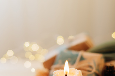 Burning candle shape of tree, gift boxes presents and Christmas decoration on w