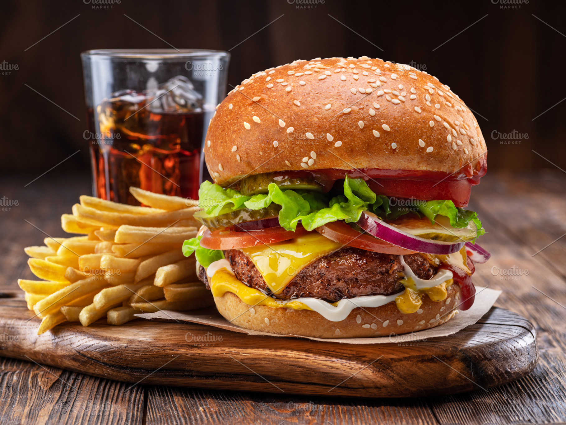 Tasty cheeseburger, glass of cola and french fries on wooden tra, a Food & Drink Photo by Volff