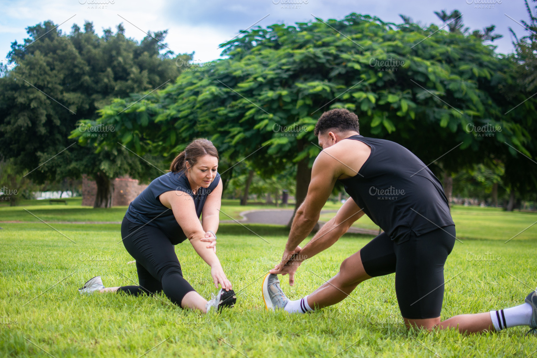 Man and woman stretching their legs together during outdoor workout, a Photo by etorres69