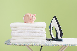 Piggy bank and iron on clean towels symbolizing household saving, a Photo by Alliance Images