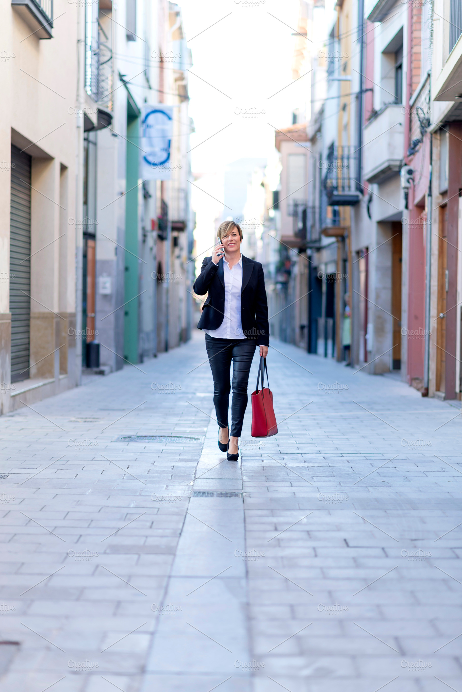Businesswoman walking and talking on smartphone, a Photo by RF Images