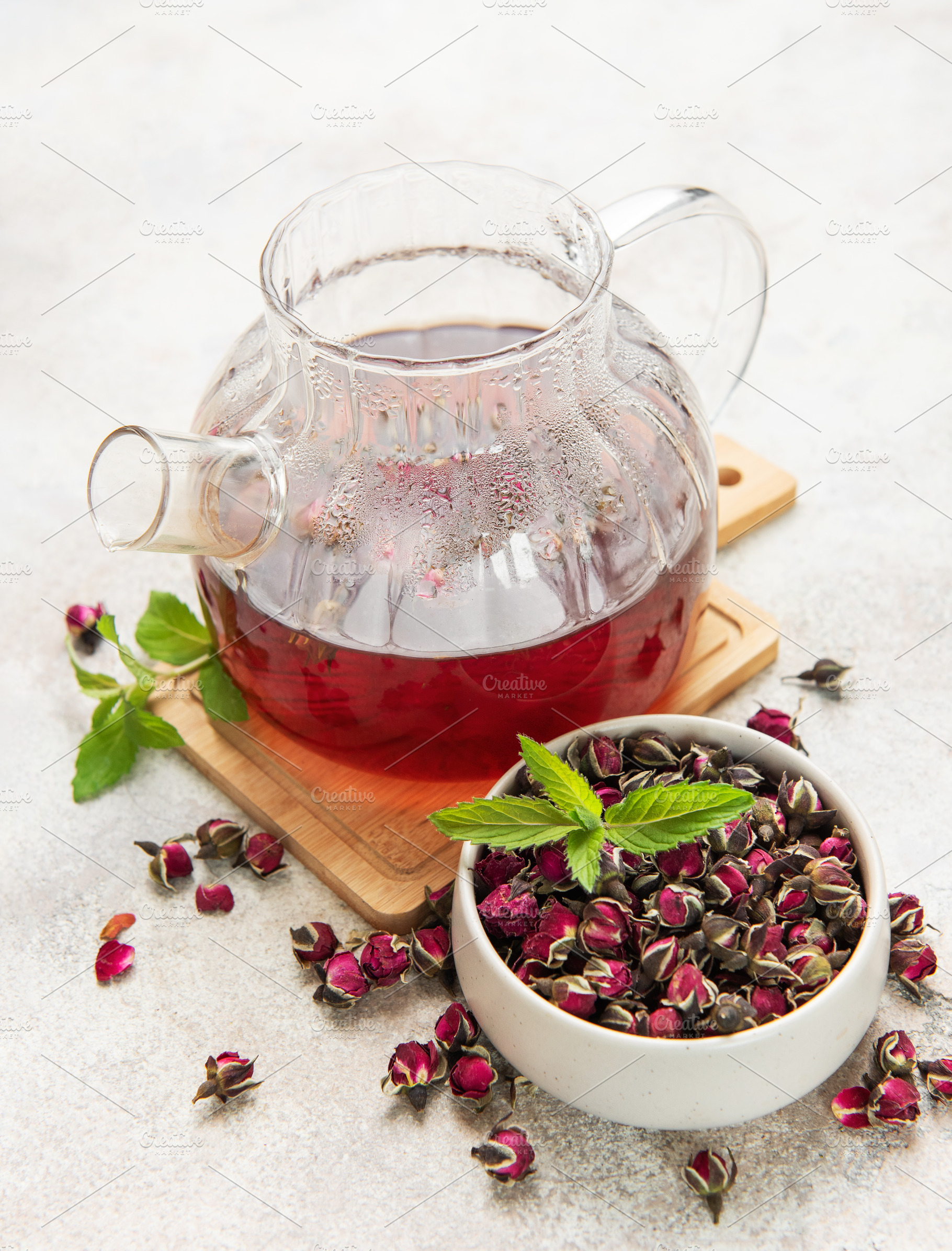 Glass teapot brewing herbal rosebud tea with mint, a Food & Drink Photo by Olena Rudo