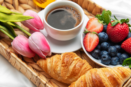 Romantic breakfast in bed with coffee, croissants, berries, hone