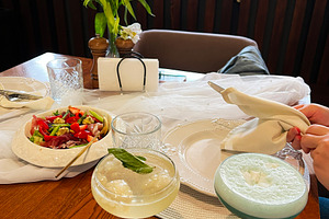 Elegant table setting with drinks, fresh salad, and white flowers centerpiece, a Photo by AS photostudio