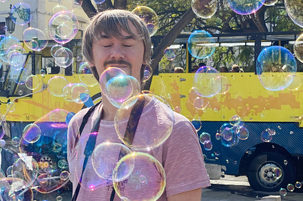 A man enjoying soap bubbles in bright sunlight