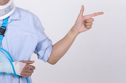 Asian man with broken arm and neck pointing finger to empty spac