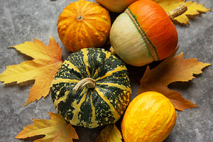 Decorative gourds and pumpkins among autumn leaves on grey backg, a Food & Drink Photo by Olena Rudo