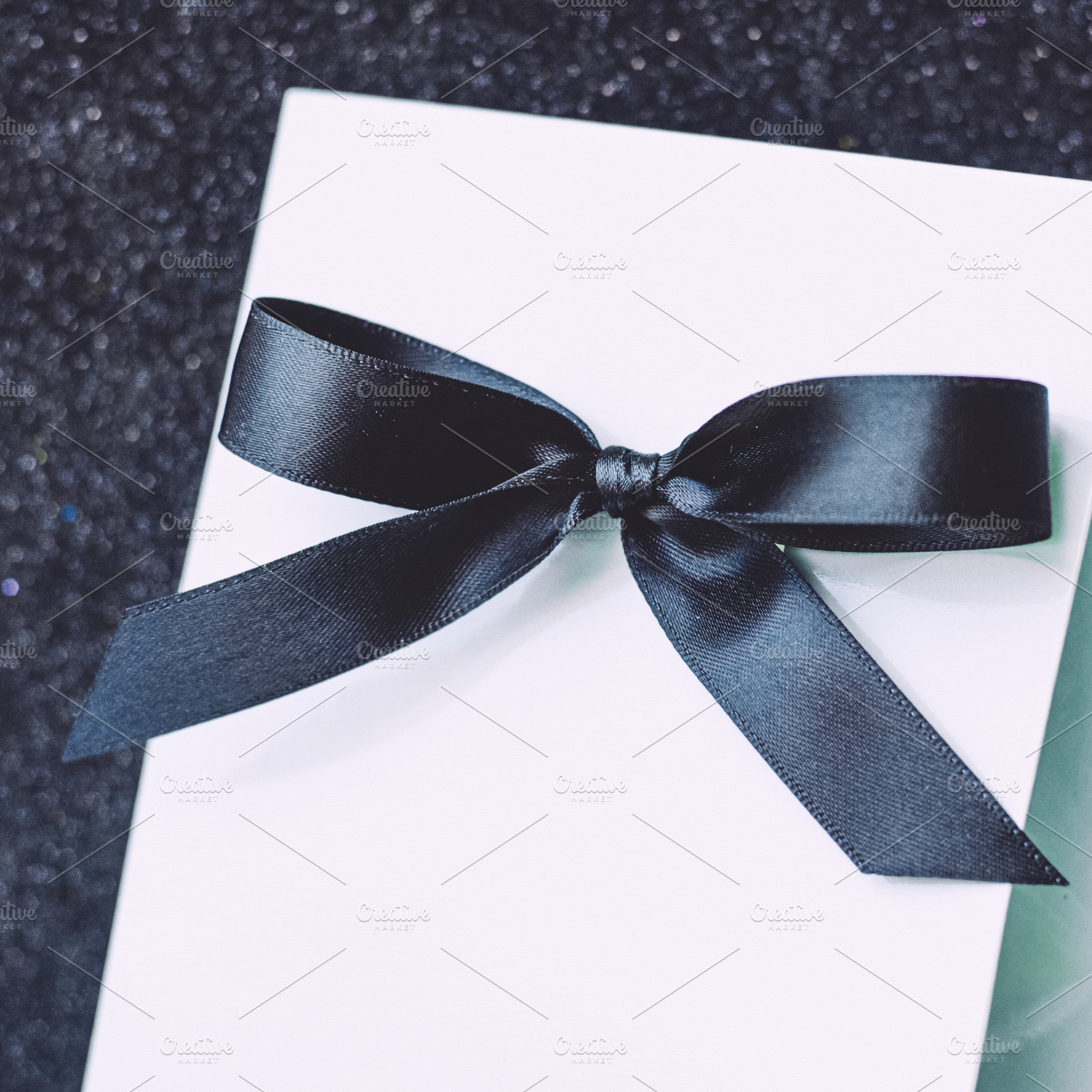 Minimalist white gift or invitation card with elegant black ribb, a Photo by Studio ANNA