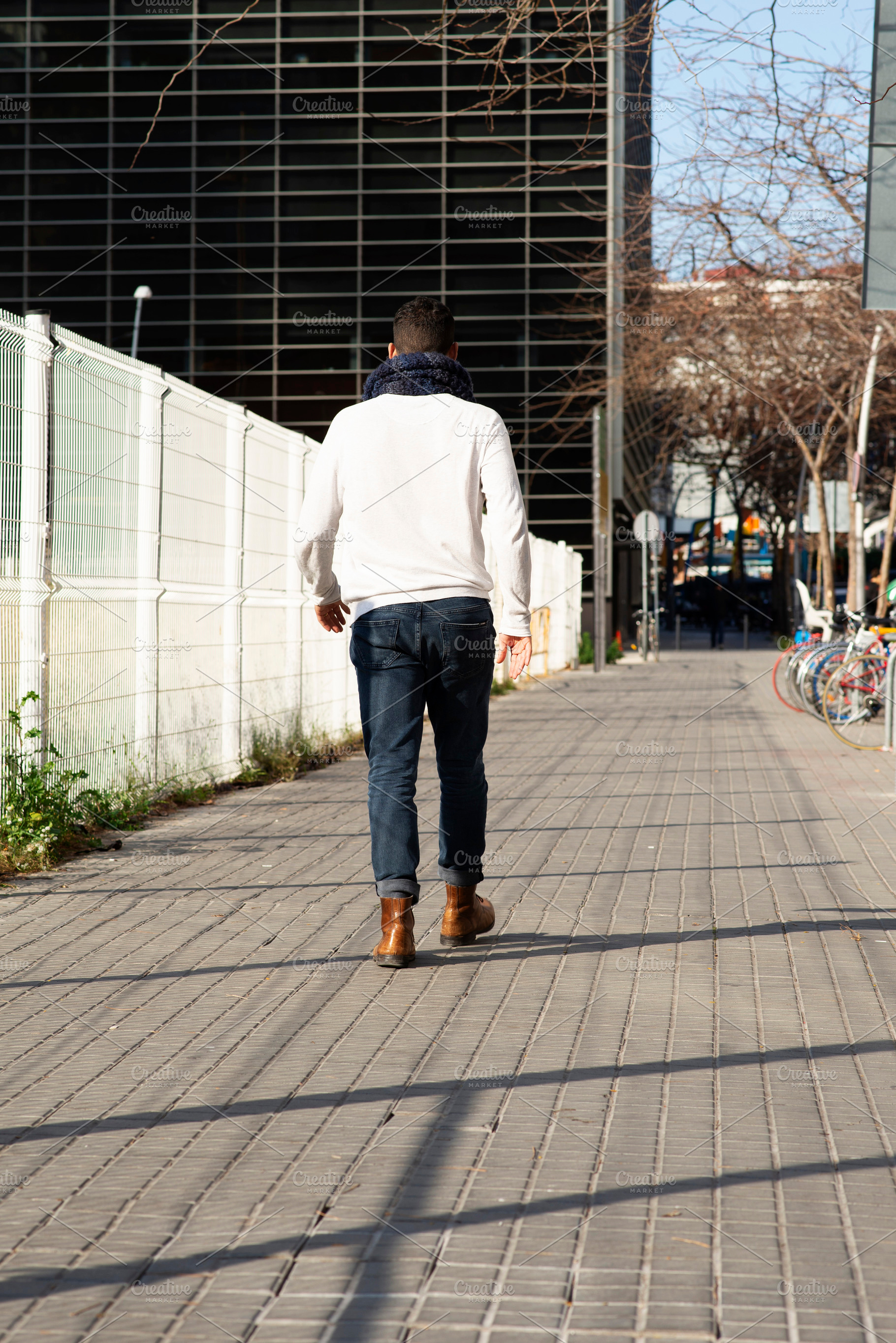Young caucasian man walking away on urban sidewalk, a Person Photo by RF Images