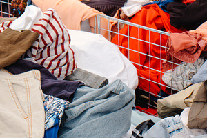 jeans and shirts filling bins at a busy outdoor stall, a Photo by Nito