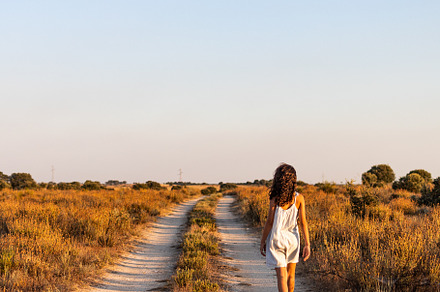 Lonely girl walking on a country road. Back view.