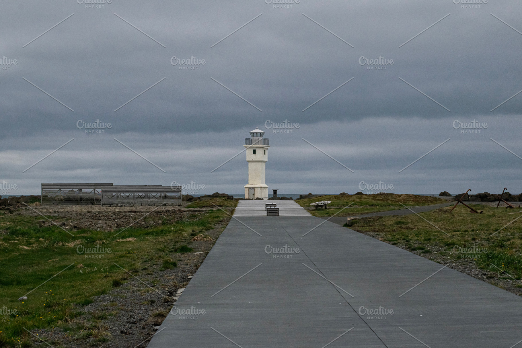 Lighthouse in Akranes Iceland with paved walkway and overcast sky, a Photo by AS photostudio