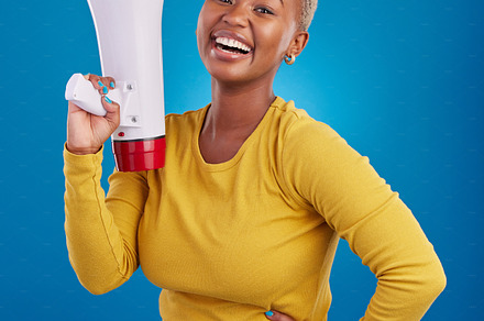 Black woman, megaphone and happy, protest and voice, freedom of speech and activism on blue background. Female smile, broadcast and speak out, rally and portrait, loudspeaker with opinion in studio, a Photo by Peopleimages.com